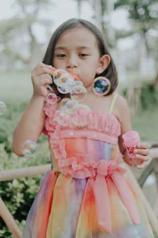 girl wearing multicolored dress making bubbles